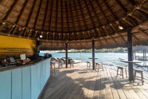 a restaurant with tables and chairs and the water at Fragata Island House in Isla Grande