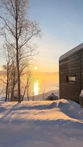 a building in the snow with the sunset in the background at Aurora Sea Lodges in Karpbukt