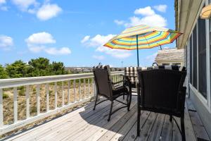 a deck with two chairs and an umbrella at 5592 - Windjammer in Nags Head