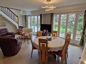 a living room with a table and chairs at Villa avec piscine proche Disneyland et Paris in Saint-Thibault-des-Vignes