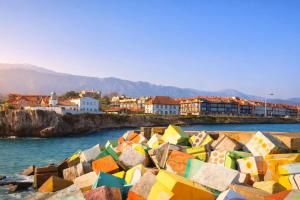 a group of rocks in the water near a city at Apartamento El Picu con piscina in Posada de Llanes