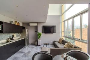 a kitchen and living room with a couch and a tv at Haven, A Design Hotel in Medellín
