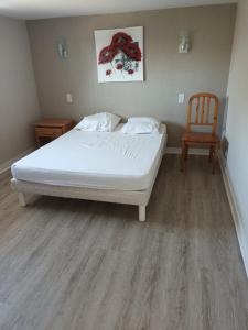 ein Schlafzimmer mit einem weißen Bett und einem Stuhl in der Unterkunft Ty Kerlen in Quimperlé