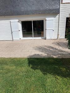 eine Garage mit weißen Toren und ein Rasengarten in der Unterkunft Ty Kerlen in Quimperlé