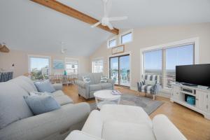 a living room with white furniture and a flat screen tv at 7158 - A Wave From It All in Waves +38 photos