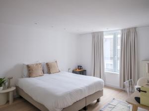 a white bedroom with a large bed and a window at Suzan's Guesthouse in Ghent