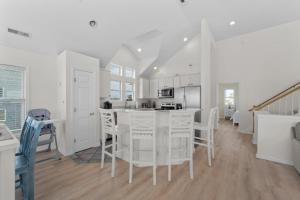 a kitchen with white cabinets and a table and chairs at 7029 - Just Breathe in Rodanthe +43 photos
