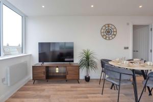 a living room with a tv and a table with chairs at Bright 2BR Apartment at Trinity Point in Gravesend +11 photos