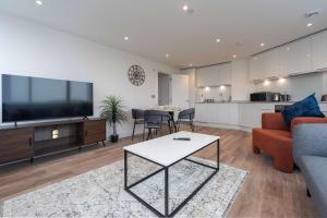 a living room with a couch and a tv and a table at Bright 2BR Apartment at Trinity Point in Gravesend
