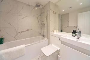 a bathroom with a tub and a sink and a toilet at Bright 2BR Apartment at Trinity Point in Gravesend