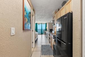 a hallway of a kitchen with a black refrigerator at Daytona Harbour Beach Resort Unit 808 in Daytona Beach +18 photos