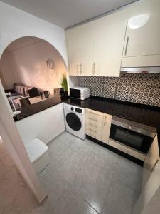 a kitchen with white cabinets and a bed in the background at Club aldeas de taray in San Javier