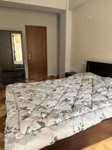 a bedroom with a large bed with a blanket on it at Saburtalo Central in Tbilisi City