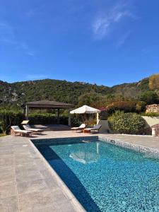 a swimming pool with two chairs and a gazebo at Spartaco Eco Retreat San Pantaleo in San Pantaleo