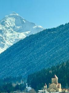 ein Berg mit einem Haus vor einem Berg in der Unterkunft Hotel Gold Tower in Mestia