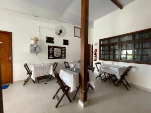 a dining room with tables and chairs and a clock on the wall at Pousada Bellmar Peró - Praia e Comércio 8 min andando in Cabo Frio