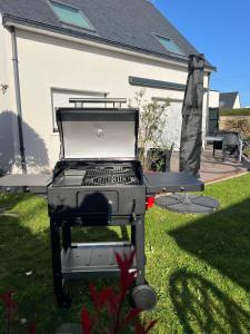 a grill sitting in the grass in a yard at MAISON NEUVE LUMINEUSE AU CALME PROCHE DES PLAGEs in Quiberon