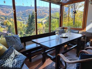 a dining room with a table and chairs and large windows at Willa Widok in Szczyrk