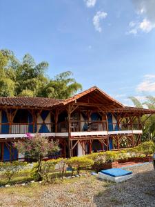 a large wooden building with a balcony and trees at La orquídea campestre in Montenegro