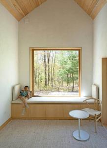 a child sitting on a window sill in a room at Architectural Cabin 18 mins to Catamount in Taghkanic