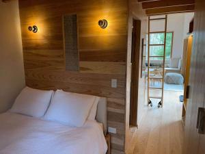 a bedroom with a white bed and a wooden wall at Architectural Cabin 18 mins to Catamount in Taghkanic