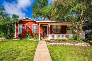 a red house with a porch and a yard at Suite Elliana w/Hot Tub & Outdoor Fireplace! in Fredericksburg