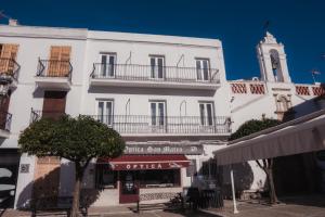 a white building with a clock tower on a street at Las Chavitas Rural Apartamentos turísticos in Alburquerque