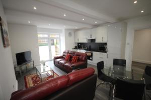 a living room with a leather couch and a glass table at Osterley Place - Apt A in Hounslow