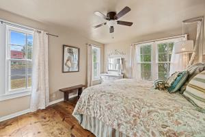 a bedroom with a bed with a ceiling fan and windows at Suite Elliana w/Hot Tub & Outdoor Fireplace! in Fredericksburg