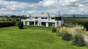 ein weißes Haus auf einem Feld mit einem Rasenhof in der Unterkunft LS Apart Hotel in Martin Miguel de Güemes International Airport
