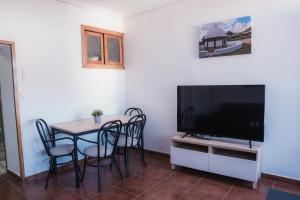 a dining room with a table and a flat screen tv at Las Chavitas Rural Apartamentos turísticos in Alburquerque
