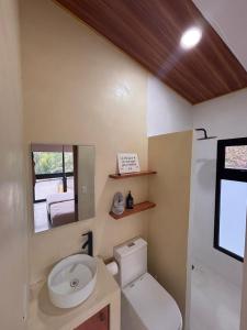 a bathroom with a toilet and a sink and a mirror at Jungle surf Villa in El Zonte
