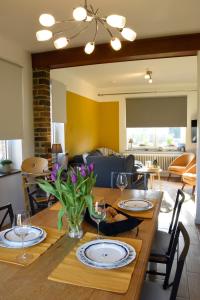 a dining room with a wooden table with plates and wine glasses at La maison du bienvenu in Namur