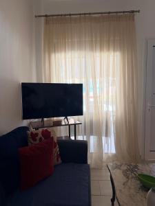a living room with a blue couch and a large window at Kallithea Cove in Kallithea Halkidikis