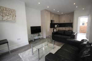 a living room with a couch and a tv at Osterley Place - Apt F in Hounslow