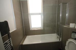 a bathroom with a tub and a toilet and a window at Osterley Place - Apt F in Hounslow +13 photos