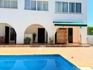 a house with a swimming pool in front of a building at Casa Maya by GMHouse Menorca in Cala Blanca