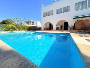 a blue swimming pool in front of a building at Casa Maya by GMHouse Menorca in Cala Blanca