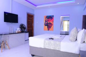 a white bedroom with a bed and a flat screen tv at De Lux Villa in Bulawayo