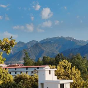 a white building with mountains in the background at The Huddle - Dawn in Dehradun