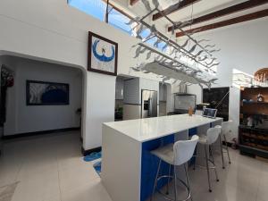 a kitchen with a white counter top and stools at Kiwara at C, Gordon's Bay in Gordonʼs Bay