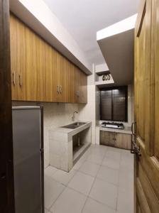 a kitchen with wooden cabinets and a sink and a refrigerator at Couple room, attached balcony in Safipur