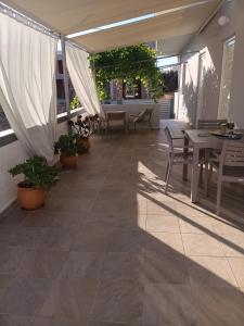 a patio with tables and chairs and white curtains at Mulberry house in Elafonisos