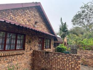a brick house with a retaining wall next to it at Primkop Cottage in White River