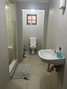 a white bathroom with a toilet and a sink at Primkop Cottage in White River