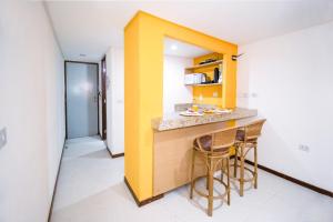 a kitchen with two stools and a yellow wall at Pipas Ocean by Pipa Centro in Pipa