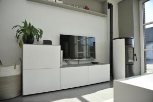 a living room with white furniture and a tv at Le Clos Sigebert in Libramont