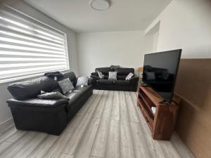 ein Wohnzimmer mit zwei Ledersofas und einem Flachbildfernseher in der Unterkunft SAMAz in Manchester