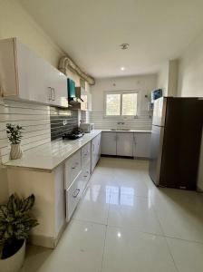 a kitchen with white cabinets and a black refrigerator at The Huddle - Dusk in Dehradun