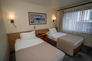 a hotel room with two beds and a window at Hotel Don Luis Puerto Montt in Puerto Montt